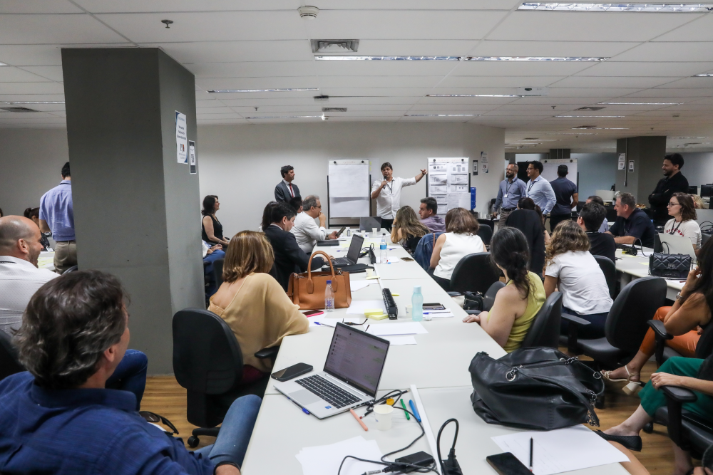 Foto de uma sala com várias pessoas reunidas discutindo melhorias do PJe