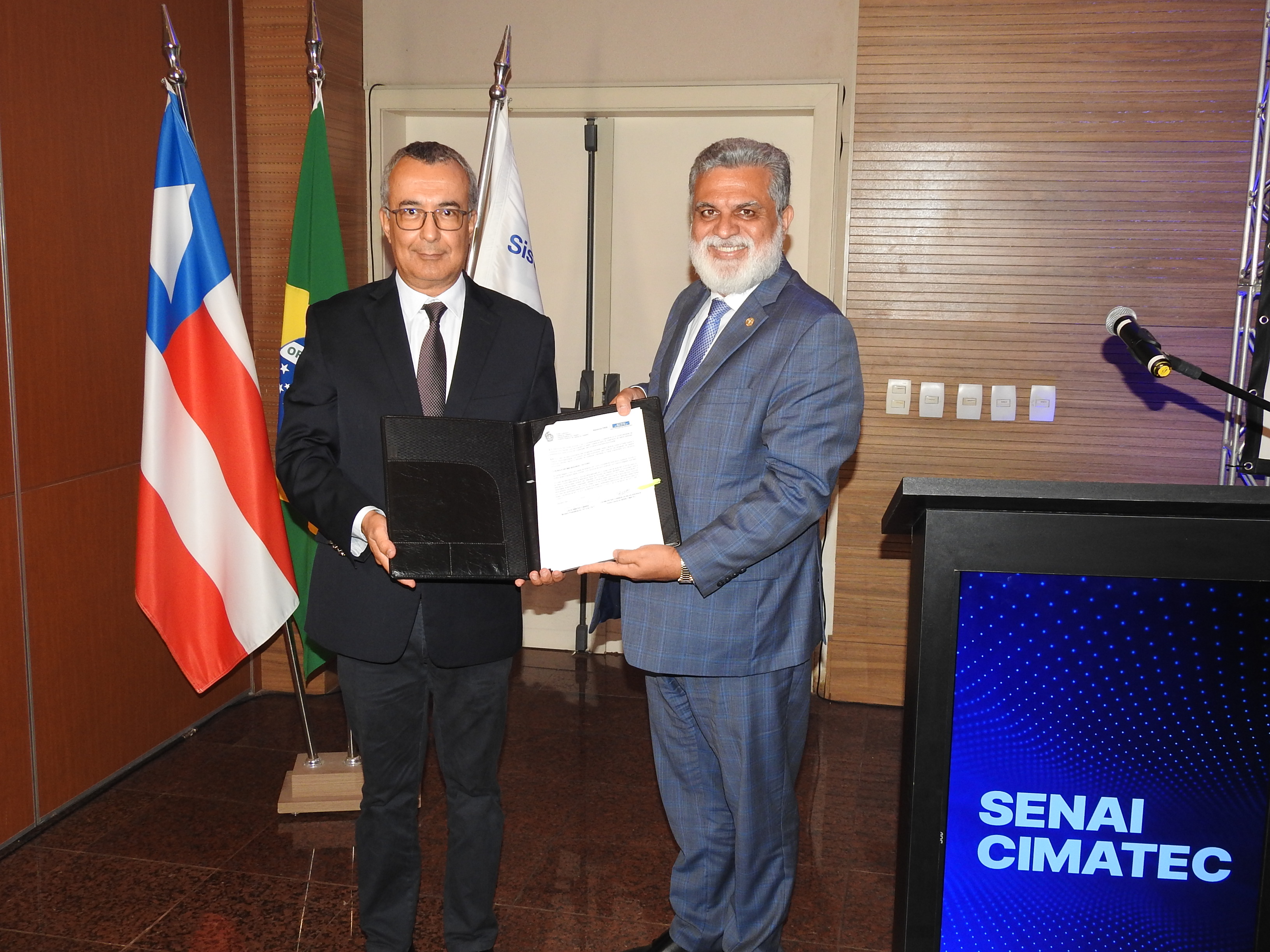 Representantes da Justiça do Trabalho e do Senai Cimatec segurando o acordo de cooperação.