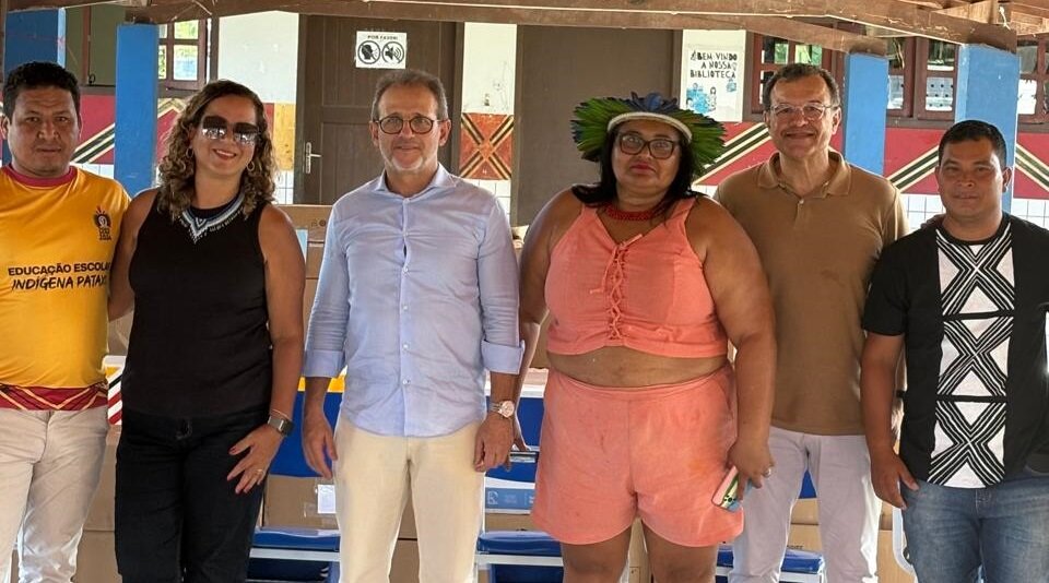 Fotografia com 6 pessoas, sendo 2 mulheres e 4 homens, para representar entrega de equipamentos de informática em escola indígena.