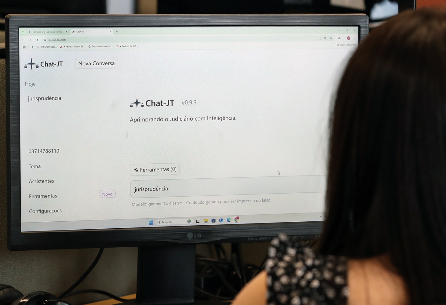 Foto de uma mulher olhando pra tela do computador e, no monitor, está a página do Chat-JT