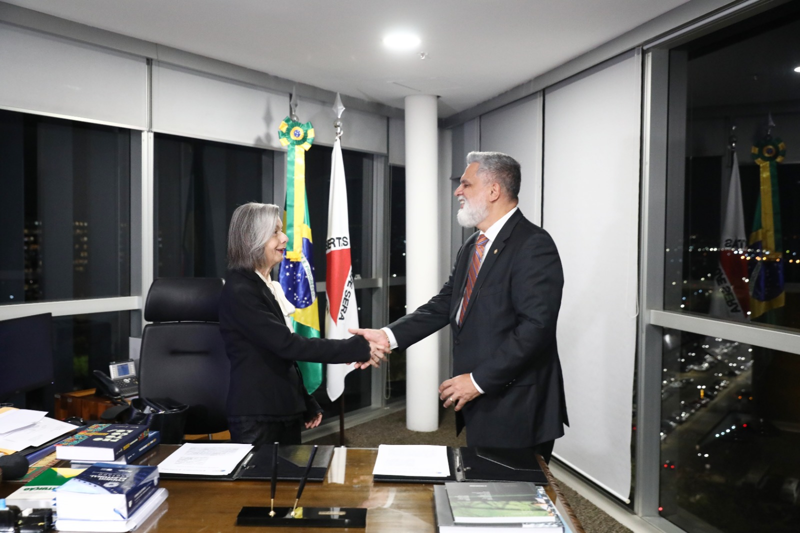 Foto da ministra Carmem Lúcio e o ministro Lelio Bentes apertando as mãos no gabinete da ministra.