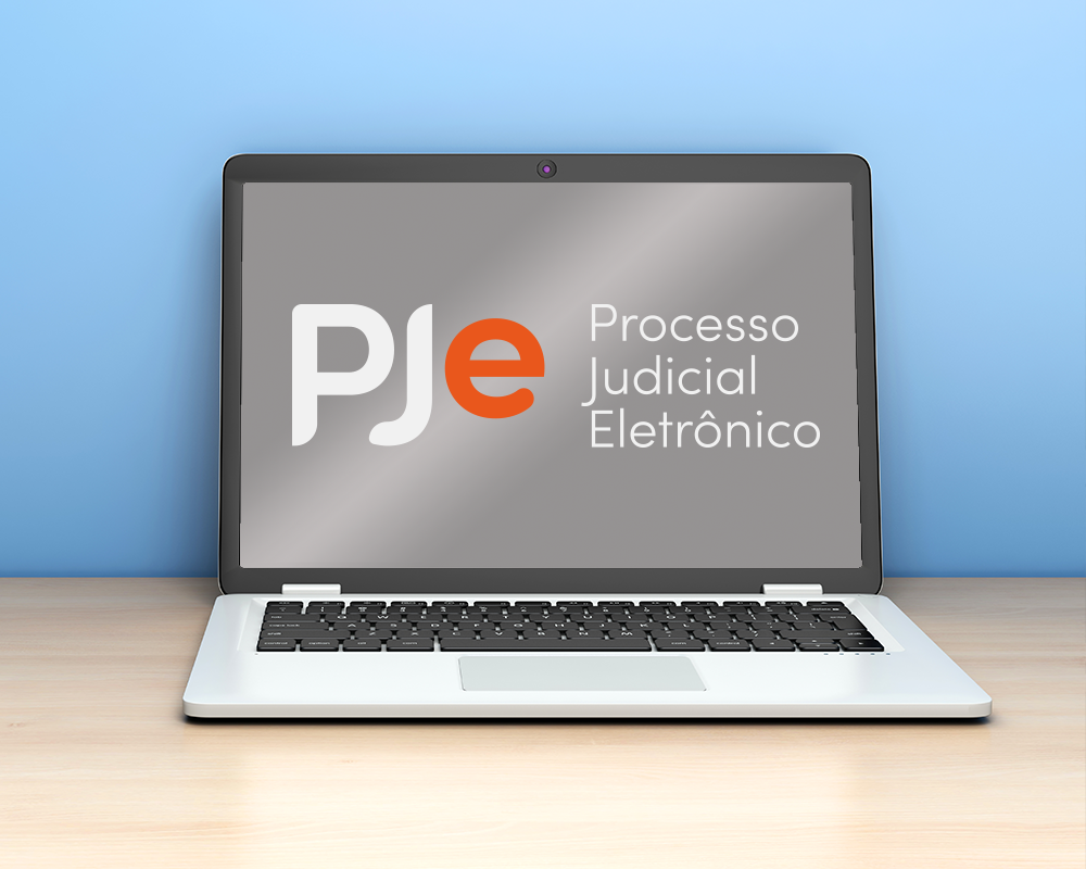 Notebook sobre a mesa com a logo do PJe na tela.