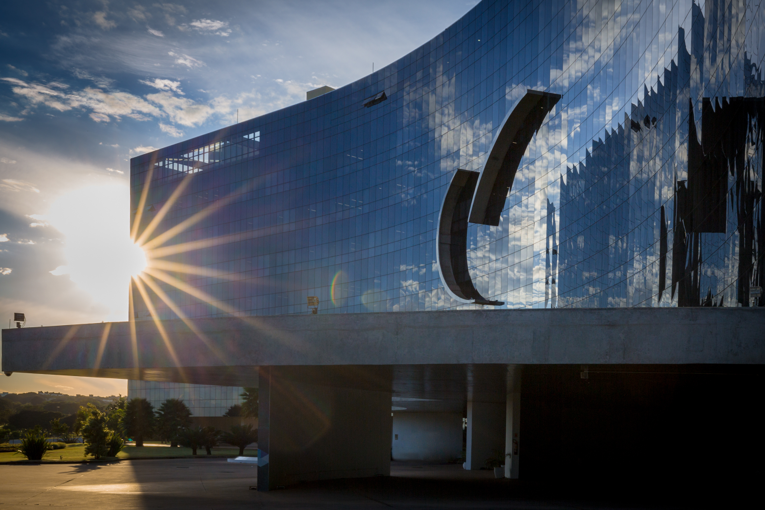 Fachada espelhada do edifício-sede do TST e do CSJT com o sol ao fundo fazendo um efeito de rajadas de luz.