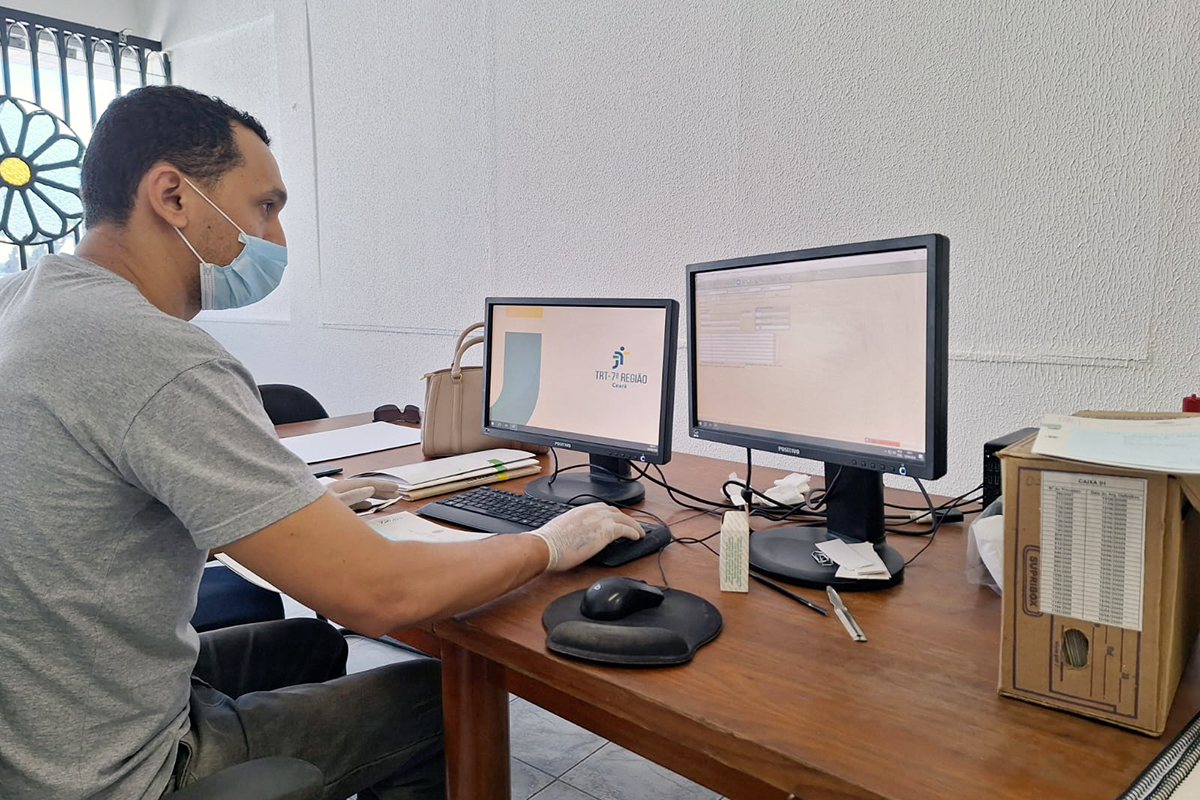 Estagiário trabalha com 2 computadores e um está aberto no TRT 7ª Região do Ceará